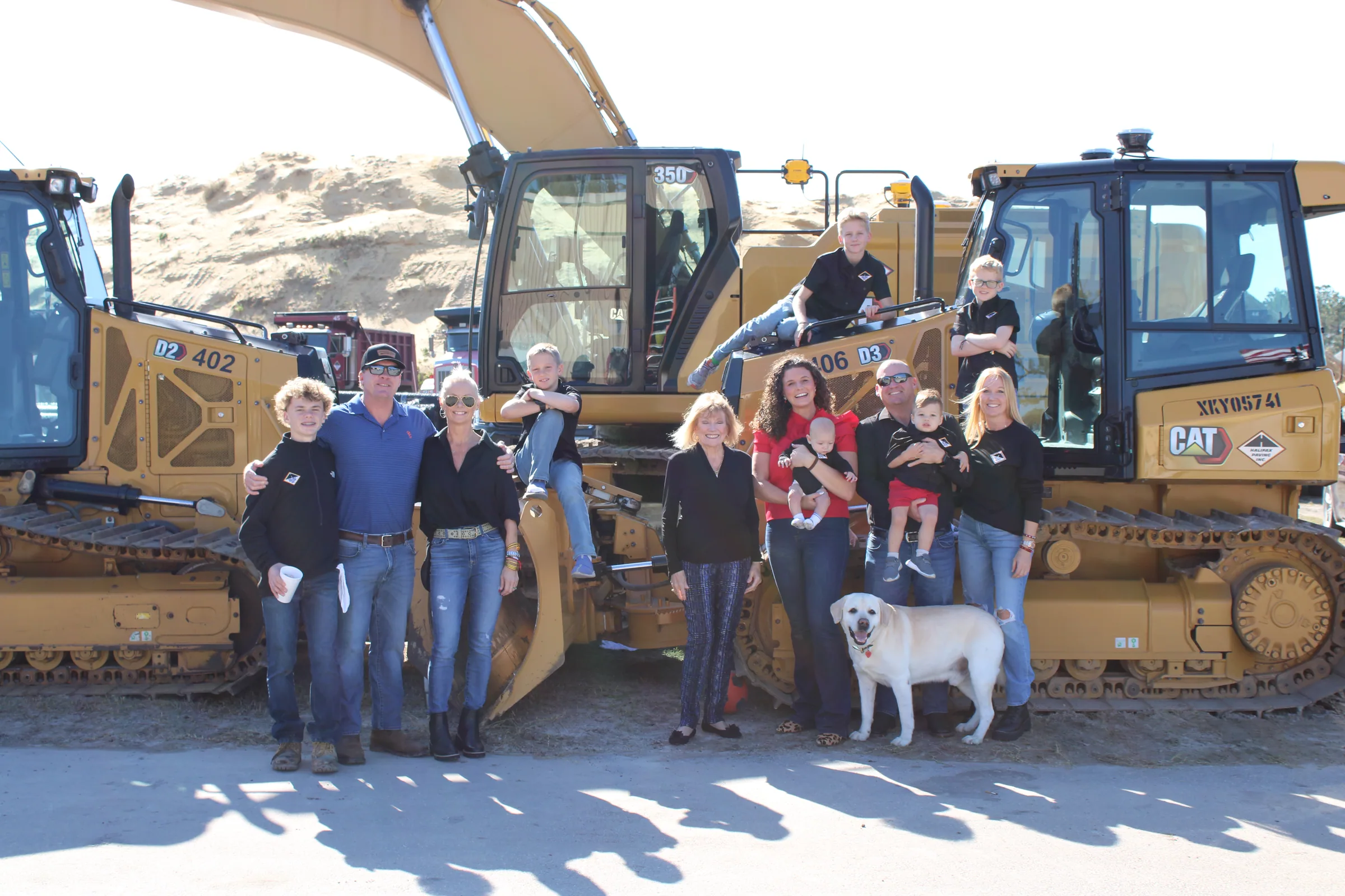 Halifax Paving team members and families with company equipment and a dog
